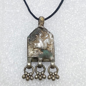 May include: Silver pendant necklace with a detailed design of a rider on a horse. The pendant has a silver chain with a decorative tassel.