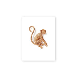 May include: A decorative monkey figurine made of woven natural-colored material. The monkey is in a seated position with its tail curled. The figurine is on a white background.