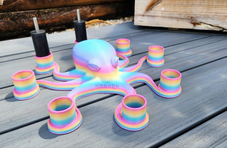 May include: A colorful octopus-shaped candle holder with rainbow-colored tentacles and candle cups. The word "KRAKEN" is printed on the base. Two black candle holders are also included. The octopus is painted in pastel colors.