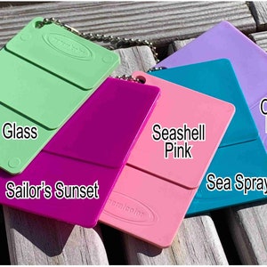 Op de afbeelding: Vijf kleurstalen van acrylverf in tinten groen, roze, magenta, teal en paars. De kleurstalen zijn gelabeld met "Beach Glass", "Sailor's Sunset", "Seashell Pink", "Sea Spray" en "Octo Ink Purple".