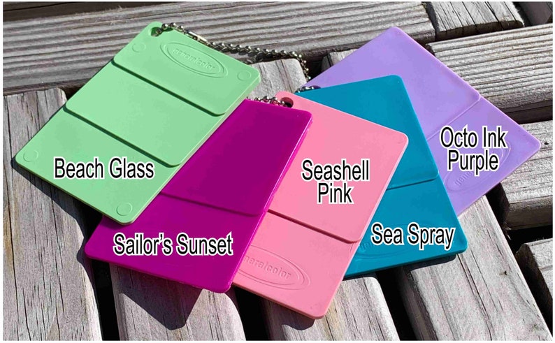 Op de afbeelding: Vijf kleurstalen van acrylverf in tinten groen, roze, magenta, teal en paars. De kleurstalen zijn gelabeld met "Beach Glass", "Sailor's Sunset", "Seashell Pink", "Sea Spray" en "Octo Ink Purple".