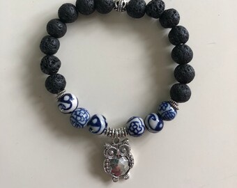 May include: Black lava rock beaded bracelet with blue and white ceramic owl charm.