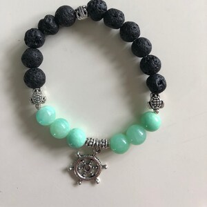 May include: A black lava rock and green jade beaded bracelet with silver turtle and ship wheel charms.