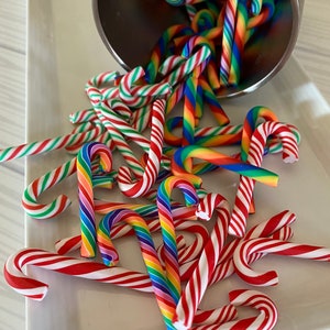 May include: A white plate filled with colorful candy canes. The candy canes are red and white, rainbow, and green and white.