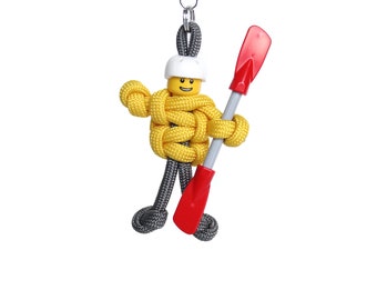 May include: A yellow and gray paracord keychain with a Lego minifigure holding a red paddle.