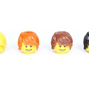 May include: Four Lego minifigure heads with different hair colors: yellow, orange, brown, and black. Each head has a yellow face with a smiling expression.
