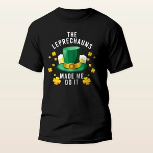 May include: Black t-shirt featuring a green leprechaun hat, two beer mugs, and shamrocks. The text reads "The Leprechauns Made Me Do It."