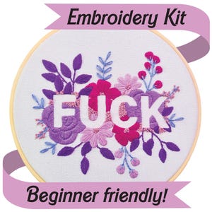 May include: Embroidery kit featuring a floral design with the word "FUCK" embroidered in white. The flowers are in shades of purple, pink, and magenta. The text "Embroidery Kit" and "Beginner friendly!" are displayed on pink ribbons.