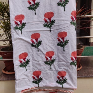May include: White cotton fabric with a repeating pattern of orange flowers with green leaves. The fabric has a white and orange trim around the edges.