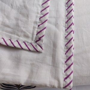 May include: White cotton fabric with a purple and white striped border. The fabric has a subtle texture.