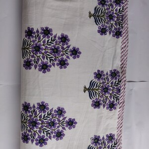 May include: White cotton fabric with a purple floral print. The fabric has a striped border in pink and white.