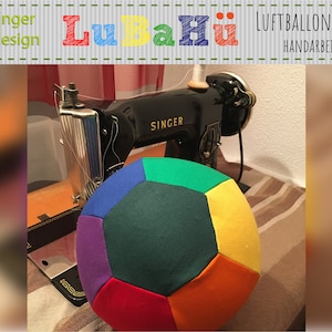 Könnte beinhalten: Ein bunter, mehrfarbiger Fussballbezug aus Stoff. Der Bezug liegt auf einem Tisch neben einer alten Singer Nähmaschine. Der Text "LuBaHü" ist im Hintergrund sichtbar.