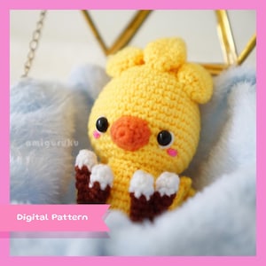 May include: A crocheted yellow chick amigurumi toy with brown and white feet. The chick is sitting on a blue fuzzy blanket. The text "Digital Pattern" is visible in the lower left corner of the image.