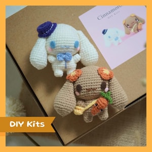 Peut inclure: Deux peluches amigurumi crochetées, l'une blanche avec un chapeau bleu et un nœud papillon, et l'autre brune avec des accents de fleurs orange, tenant une carotte. Kits DIY Cinnamoroll.