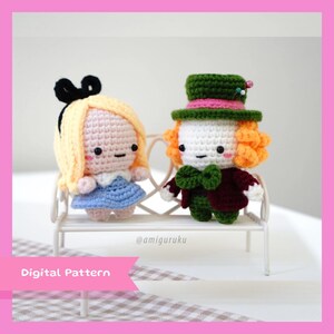 Può includere: Bambole amigurumi all'uncinetto di Alice nel Paese delle Meraviglie e il Cappellaio Matto. Alice indossa un vestito blu con un grembiule bianco e un fiocco nero. Il Cappellaio Matto indossa un cappello verde con una fascia rosa, un gilet verde e una giacca rossa. Le bambole sono sedute su una panchina bianca. @amiguruku Modello digitale