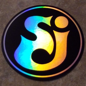 May include: A round, black and silver sticker with a holographic, rainbow-colored design of the letters "SJ" in a stylized font.