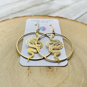 May include: A set of three ceramic mugs with a speckled, matte finish. The mugs are in shades of cream, light brown, and dark brown. Each mug has a simple, minimalist design and a rounded handle. The mugs are likely for coffee or tea.