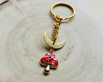May include: Gold keyring with a crescent moon charm and a red mushroom charm with white and yellow polka dots.