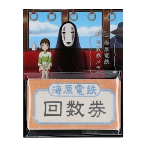 Può includere: Un biglietto del treno in stile vintage con testo giapponese che recita "Sea Origin Electric Railway Return Ticket". Il biglietto è in una custodia di plastica con l'immagine di un personaggio del film d'animazione La città incantata.