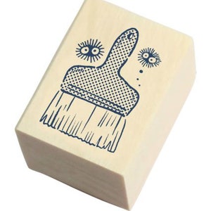 May include: A wooden stamp with a blue illustration of a paintbrush. The paintbrush has a textured handle and bristles. There are two small blue illustrations of eyes above the paintbrush.