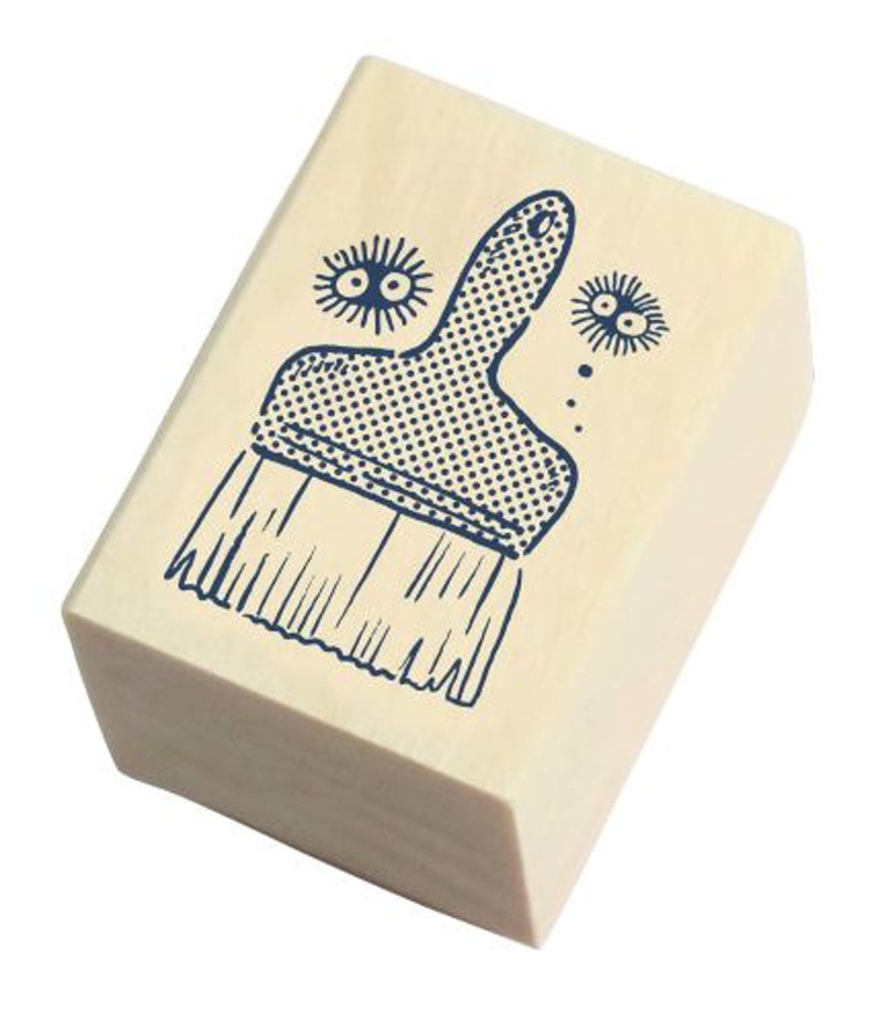 May include: A wooden stamp with a blue illustration of a paintbrush. The paintbrush has a textured handle and bristles. There are two small blue illustrations of eyes above the paintbrush.