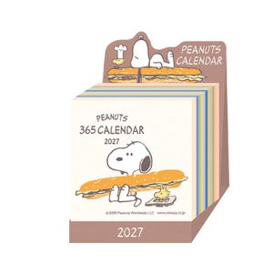 May include: A Peanuts 365 calendar for 2027 featuring Snoopy and Woodstock. The cover shows Snoopy holding a large sandwich with Woodstock nearby. The top header displays the Peanuts Calendar text. The base is brown with the year 2027 printed on it.
