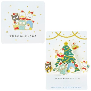May include: Two white Christmas cards with cartoon characters. One card features a group of characters with text in Japanese. The other card has a Christmas tree and characters with the text "MERRY CHRISTMAS" and Japanese text.