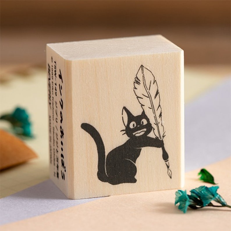 May include: A wooden stamp with a black cat holding a feather quill. The stamp is labeled "Ink's a-bochin" and "TSW-149 Ghibli/Jiji".