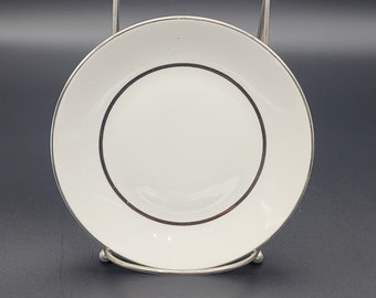 Puede incluir: Un platillo de porcelana blanca con una fina banda negra alrededor del borde.