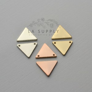 以下が含まれることがあります： 2つの穴がそれぞれ開いた三角形の金属製のブランクが4つ。ブランクはシルバー、ゴールド、2色の銅です。