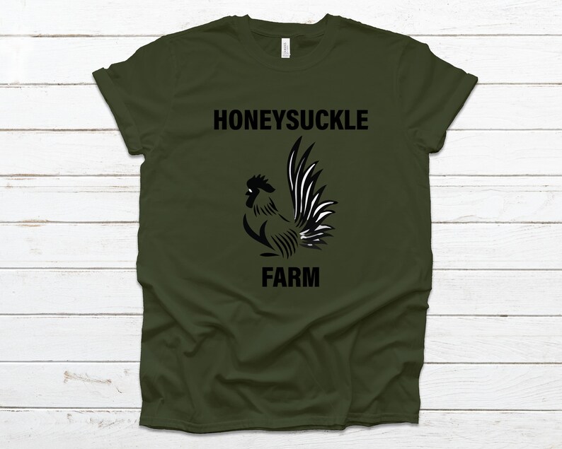 Pu&ograve; includere: Una maglietta verde con un grafico di gallo nero e il testo "Honeysuckle Farm".