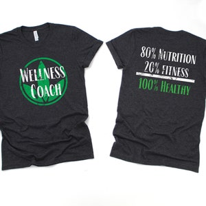 May include: A dark heather grey t-shirt with a green leaf logo and the text "Wellness Coach" on the front. The back of the shirt has the text "80% Nutrition 20% Fitness 100% Healthy" in white with a green line.