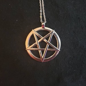 May include: A silver chain necklace with a pendant featuring a pentagram inside a circle.
