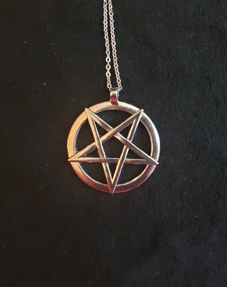 May include: A silver chain necklace with a pendant featuring a pentagram inside a circle.