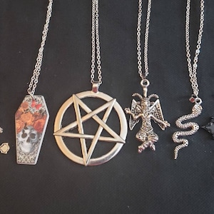 May include: Six silver and black pendant necklaces with various designs, including a pentagram, a coffin, a skull, a goat, a snake, and a cross.