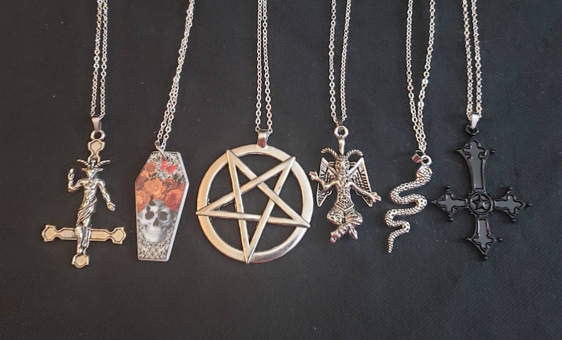 May include: Six silver and black pendant necklaces with various designs, including a pentagram, a coffin, a skull, a goat, a snake, and a cross.