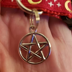 Puede incluir: Un amuleto de pentagrama plateado en un llavero plateado. El amuleto es una estrella de cinco puntas con un c&iacute;rculo alrededor.