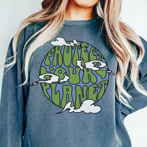 May include: A blue sweatshirt with a green and blue graphic of the Earth with the text "Protect Our Planet" in a retro font.