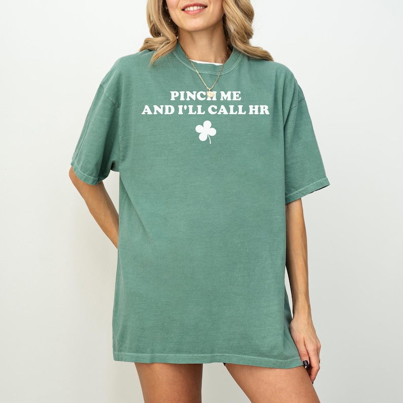 Peut inclure: Un t-shirt vert avec le texte "Pinch me and I'll call HR" et un tr&egrave;fle blanc.