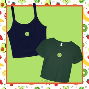 May include: A navy blue crop top with spaghetti straps and a dark green t-shirt, both featuring a lime slice graphic. The shirts are set against a light green background with a fruit-themed border.