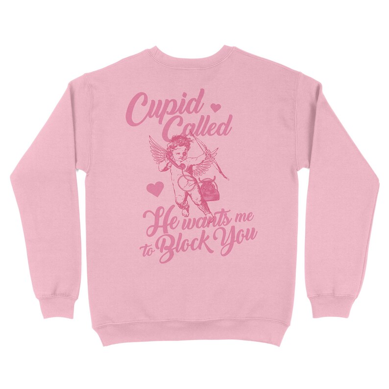 May include: Pink sweatshirt with a graphic of a cupid with a heart and the text "Cupid Called He wants me to Block You".