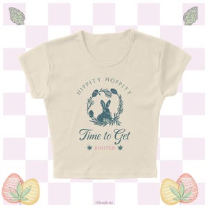 May include: A cream-colored cropped t-shirt with a blue graphic of a bunny rabbit in a wreath with the text "Hippity Hoppity Time to Get Zooted".