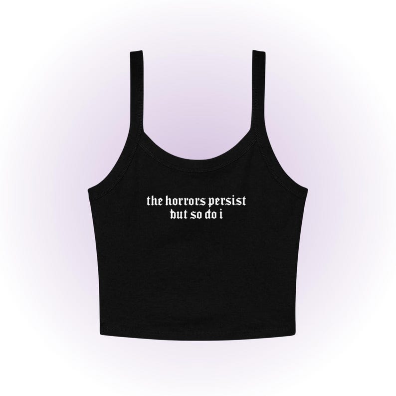 May include: Black crop top with thin straps. The white text "the horrors persist but so do i" is centered on the front. The top is made of a soft, likely cotton, material.