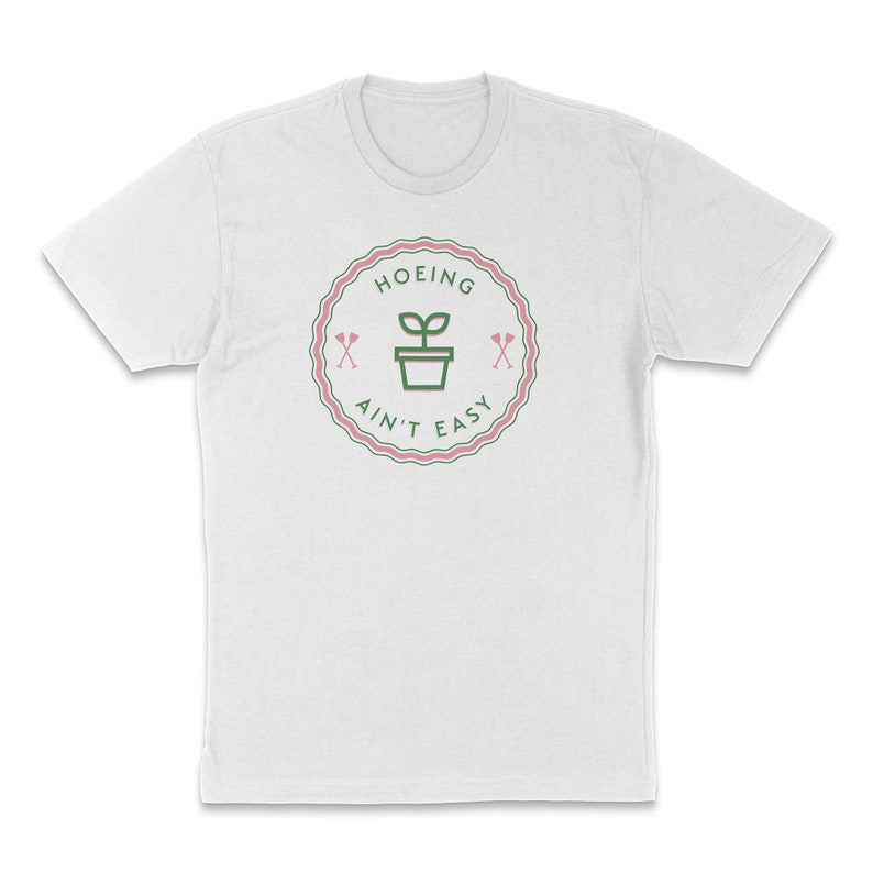 May include: White t-shirt with a green and pink graphic of a plant in a pot with the text "HOEING AIN'T EASY" in a circle.
