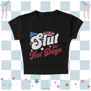 May include: Black crop top with the phrase "Slut for Hot Dogs" in white and red lettering, with an American flag design. The top has a scoop neck and short sleeves. The text is stylized with stars.