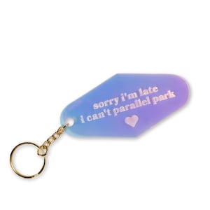 May include: A blue and purple iridescent keychain shaped like a motel key with the text "sorry i'm late i can't parallel park" and a small heart.