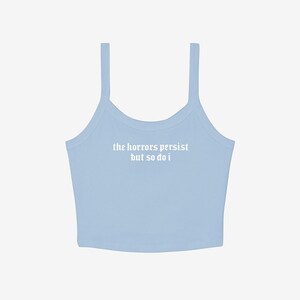 May include: A light blue camisole top with thin straps. The text "the horrors persist but so do i" is printed in white across the front. The top is made of a soft, ribbed material.