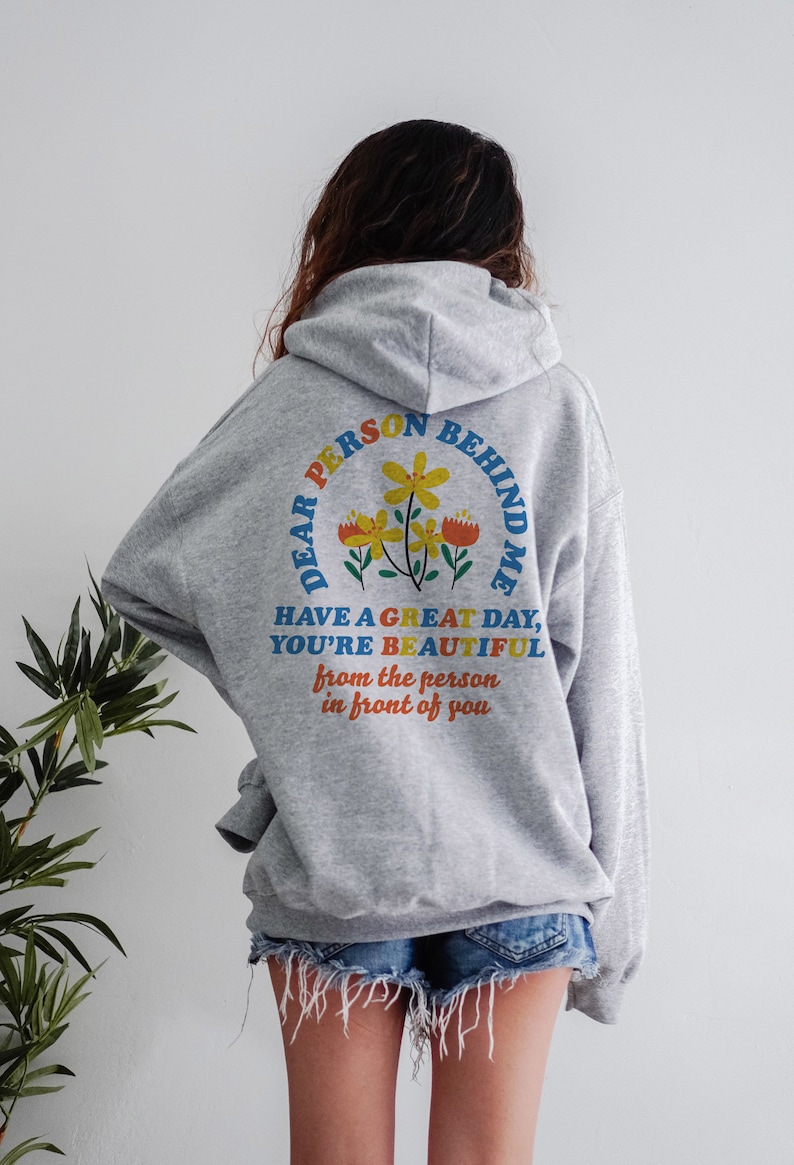 May include: Gray hooded sweatshirt with a colorful graphic on the back that says "Dear Person Behind Me Have a Great Day, You're Beautiful from the person in front of you".