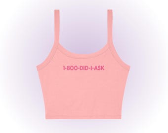 Puede incluir: Un top corto de color rosa claro con tirantes finos. El texto "1-800-DID-I-ASK" está impreso en un rosa más oscuro en la parte delantera. El top está hecho de un material suave y tiene un escote redondo.