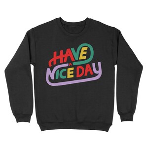 May include: Black sweatshirt with a colourful graphic that says "HAVE A NICE DAY" in a retro font.